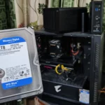 Người dùng đang cầm ổ cứng HDD trước máy tính và hai thiết bị NAS TerraMaster