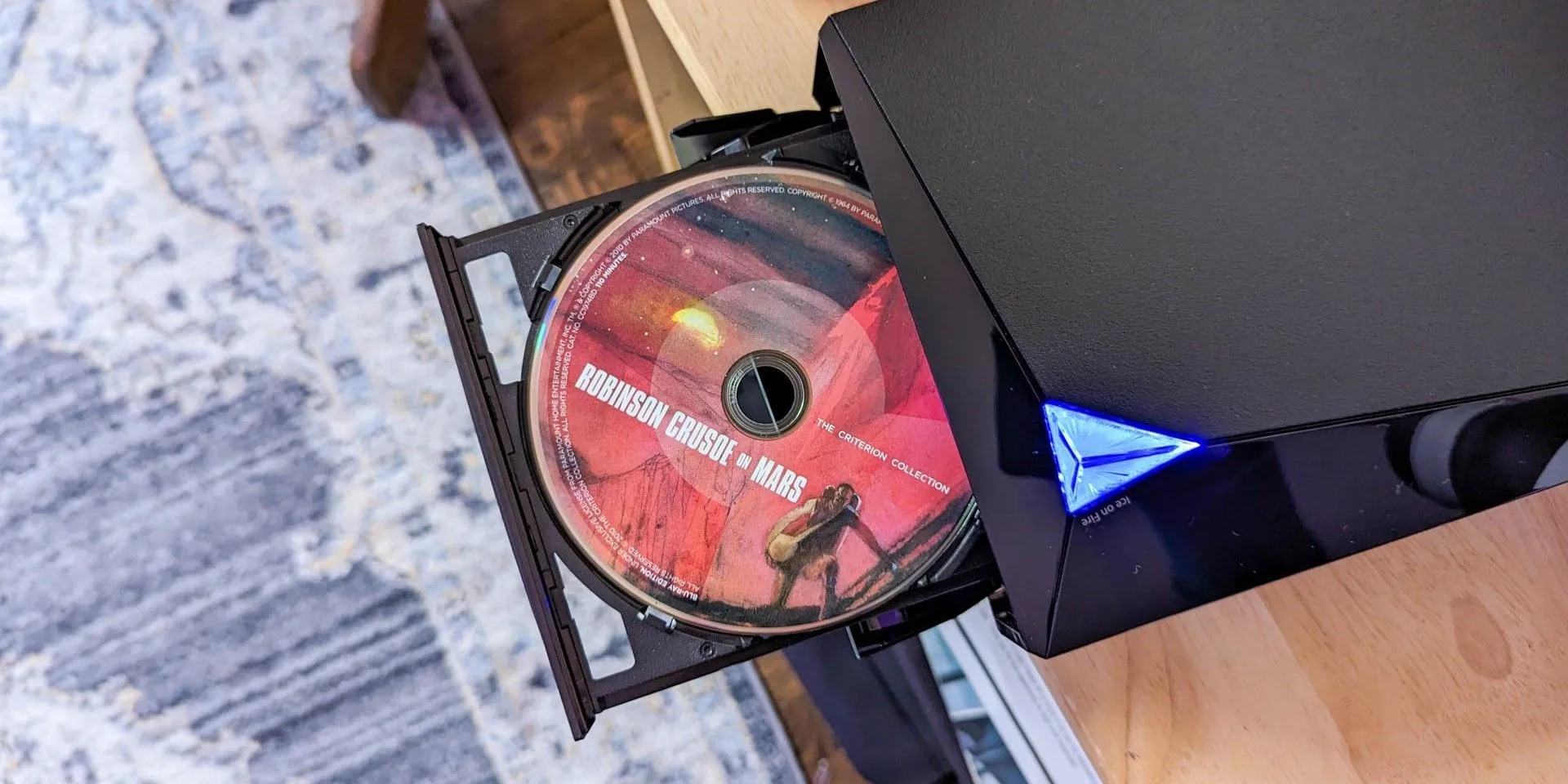 Đầu đĩa DVD Asus với đĩa phim đang nằm trong khay, kết nối với màn hình để xem phim.