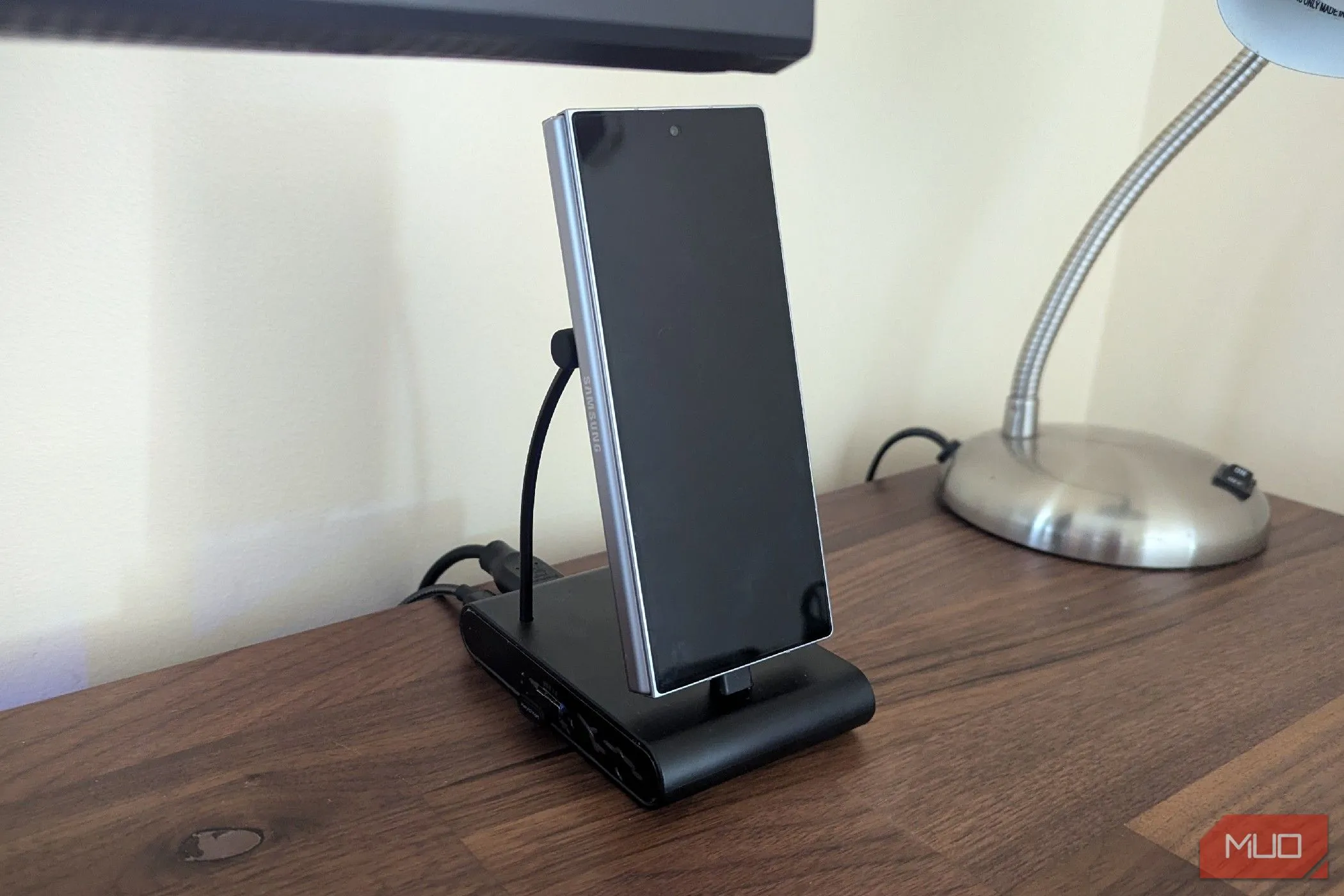Điện thoại Samsung Galaxy Z Fold 6 đặt thẳng đứng trên docking station USB-C màu đen, sạc và kết nối ngoại vi.