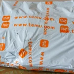 Hộp hàng Temu đặt trên bàn, tượng trưng cho trải nghiệm mua sắm trực tuyến từ các sàn thương mại điện tử quốc tế và rủi ro liên quan đến bảo vệ người tiêu dùng.