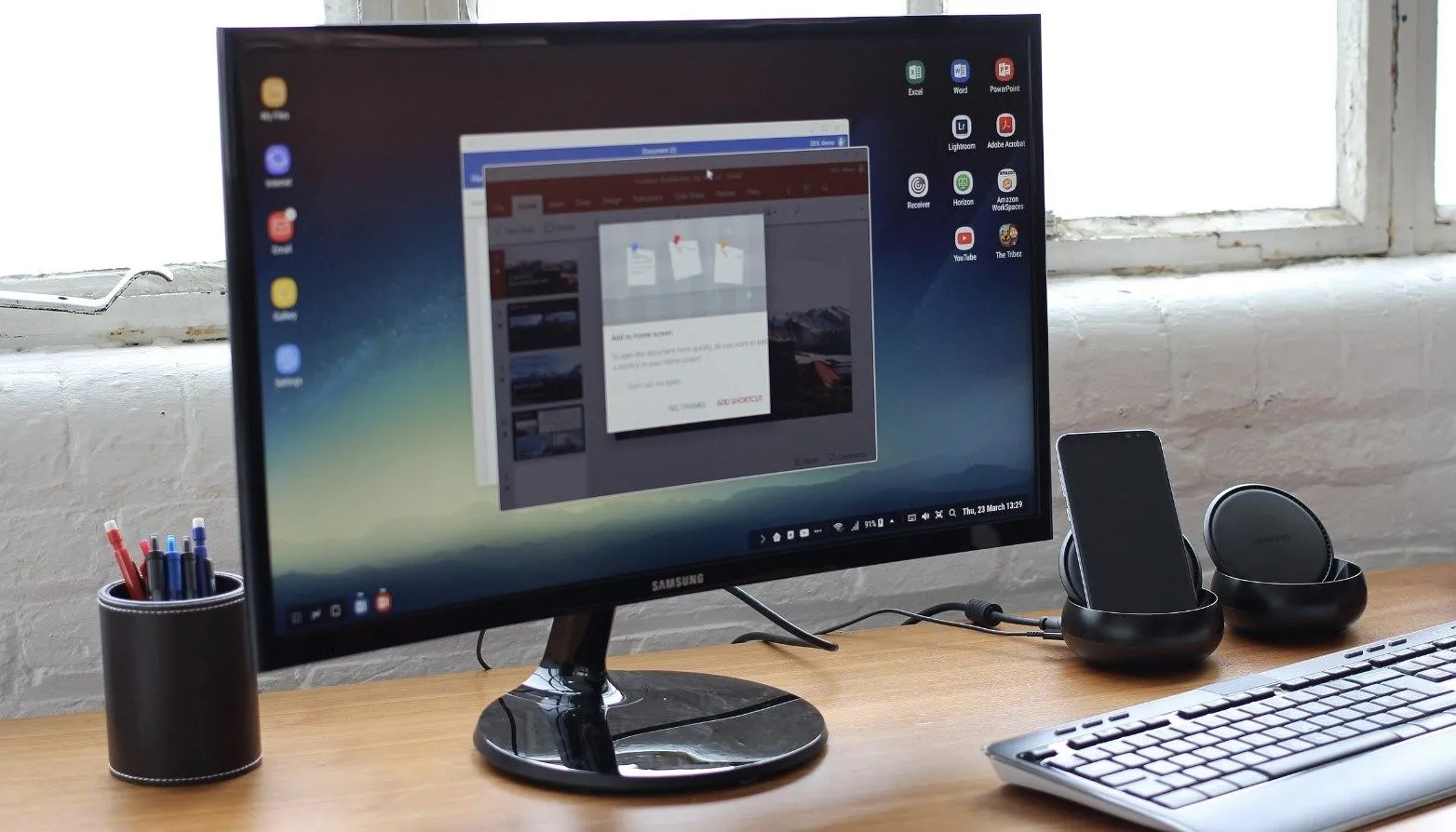 Màn hình Samsung hiển thị giao diện DeX, kèm bàn phím và hệ thống loa, biến điện thoại thành máy tính để bàn.