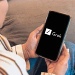 Một người đang xem điện thoại thông minh hiển thị logo Grok AI