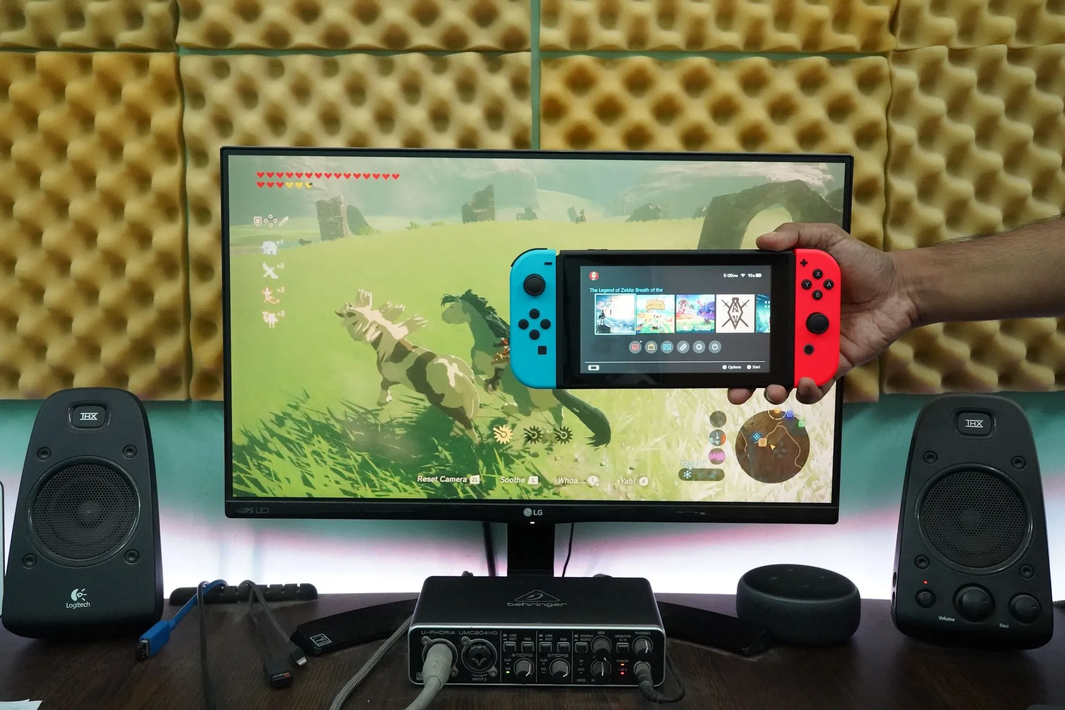 Người đàn ông đang cầm Nintendo Switch chơi game trên màn hình máy tính, tối ưu trải nghiệm gaming.