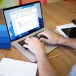 Người dùng làm việc trên Microsoft Word, laptop và biểu tượng Word trên bàn