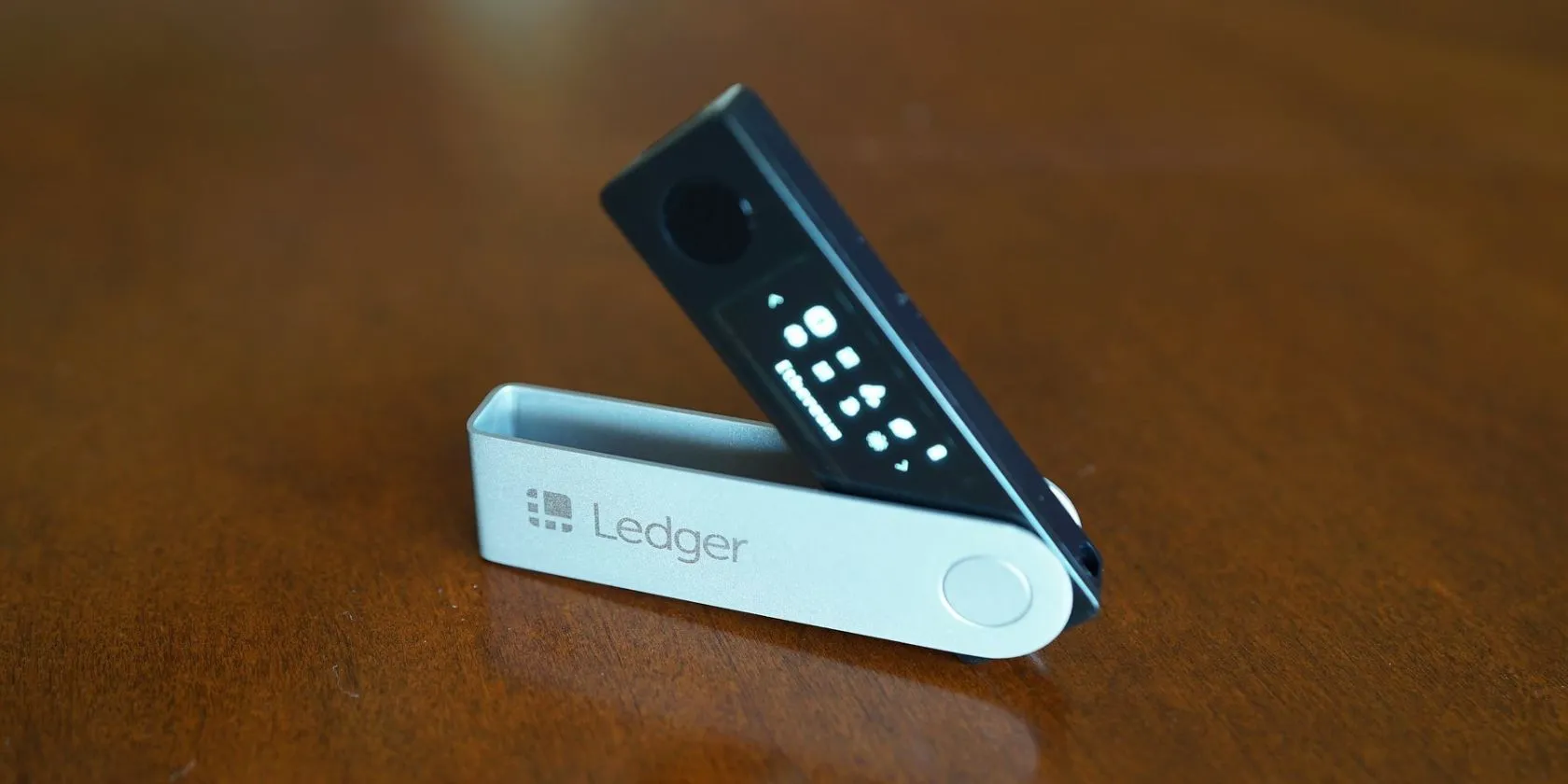 Thiết bị ví lạnh Ledger Nano X màu đen đặt trên bề mặt gỗ, tượng trưng cho bảo mật tiền điện tử.