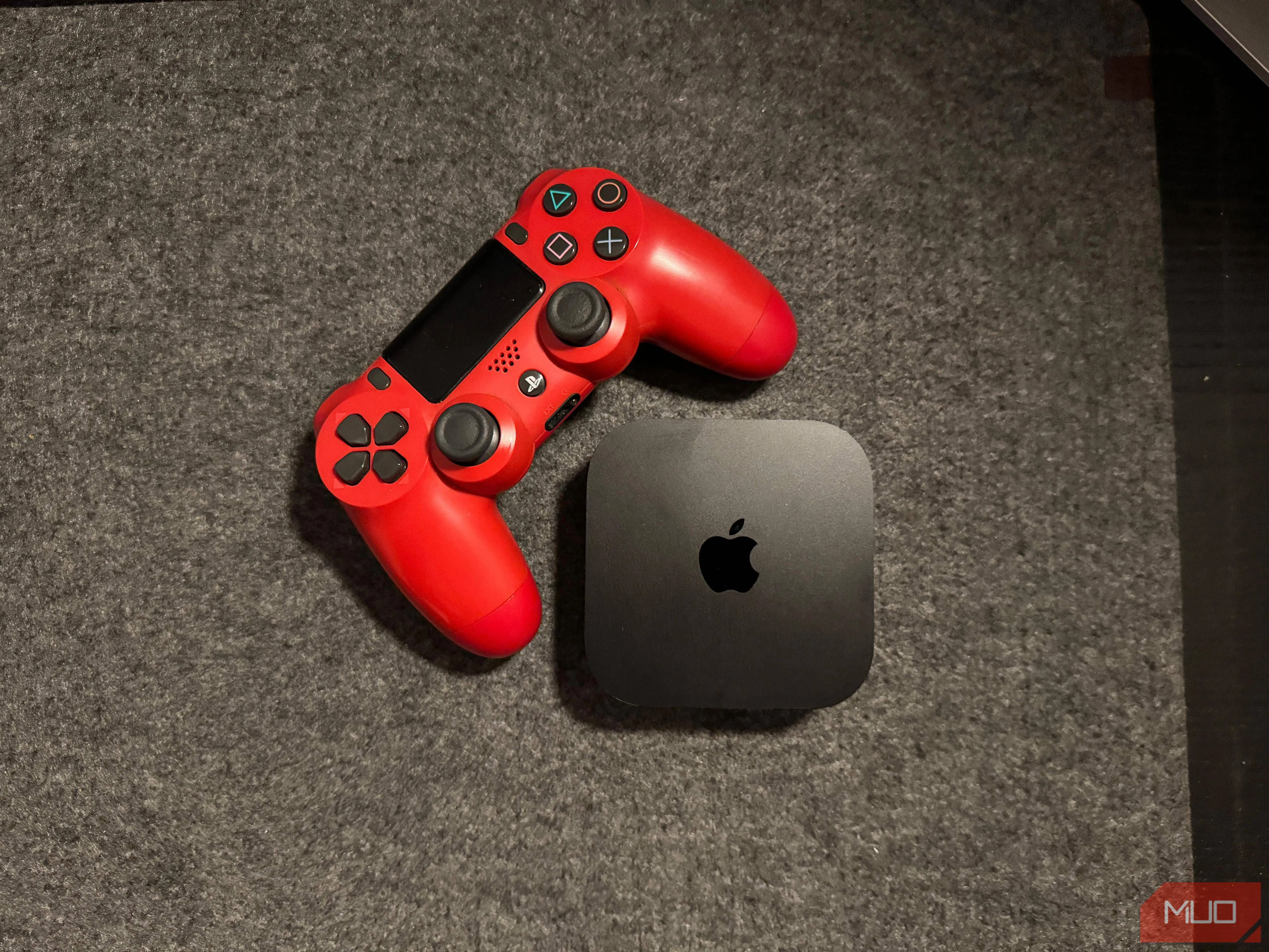 Apple TV đặt cạnh tay cầm chơi game PlayStation 4, minh họa khả năng gaming của thiết bị