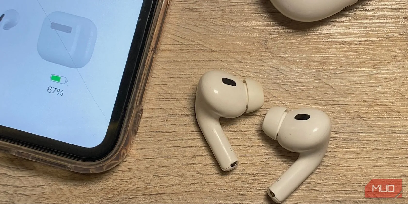 Các mẫu AirPods khác nhau đặt trên bàn gỗ cùng iPhone, minh họa sự khác biệt về thiết kế
