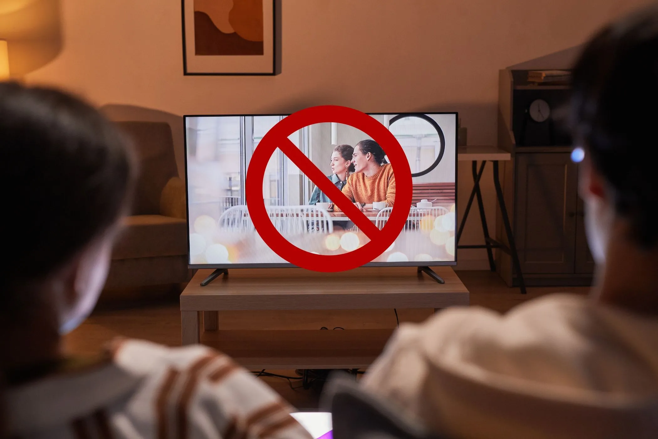 Cặp đôi đang xem TV với biểu tượng gạch chéo trên màn hình, tượng trưng cho việc vô hiệu hóa tính năng theo dõi Smart TV