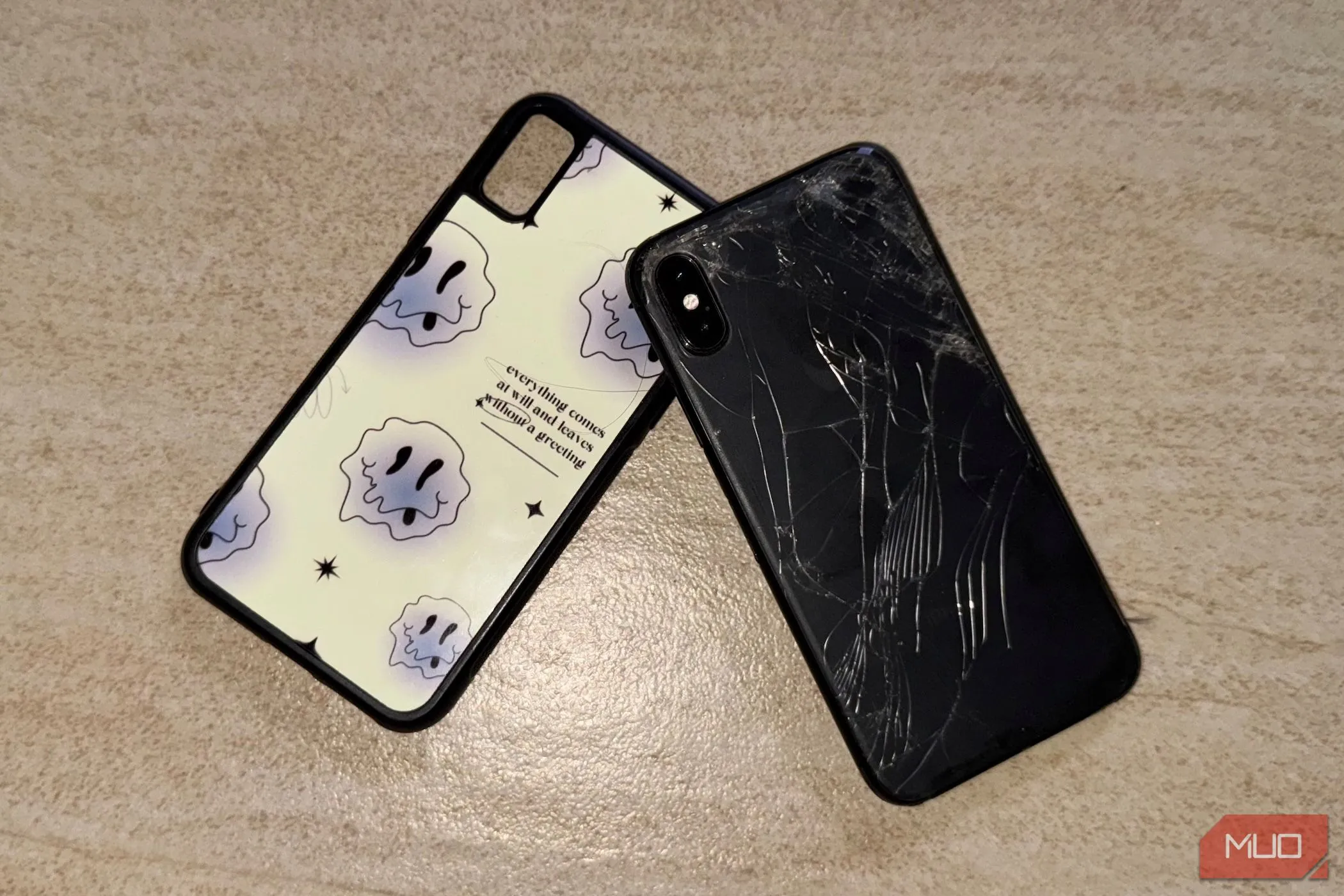 Chiếc iPhone X với mặt lưng kính bị nứt nằm trên sàn, gần ốp lưng