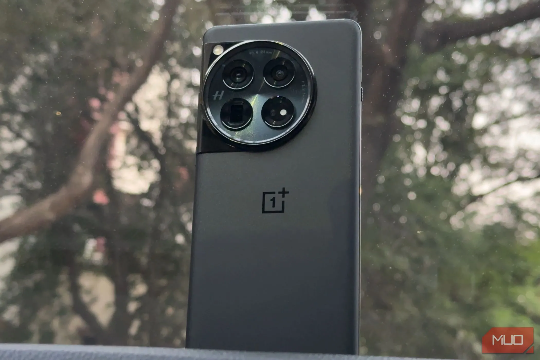 Điện thoại OnePlus 12 màu đen với cụm camera tròn đặt trên bảng điều khiển ô tô