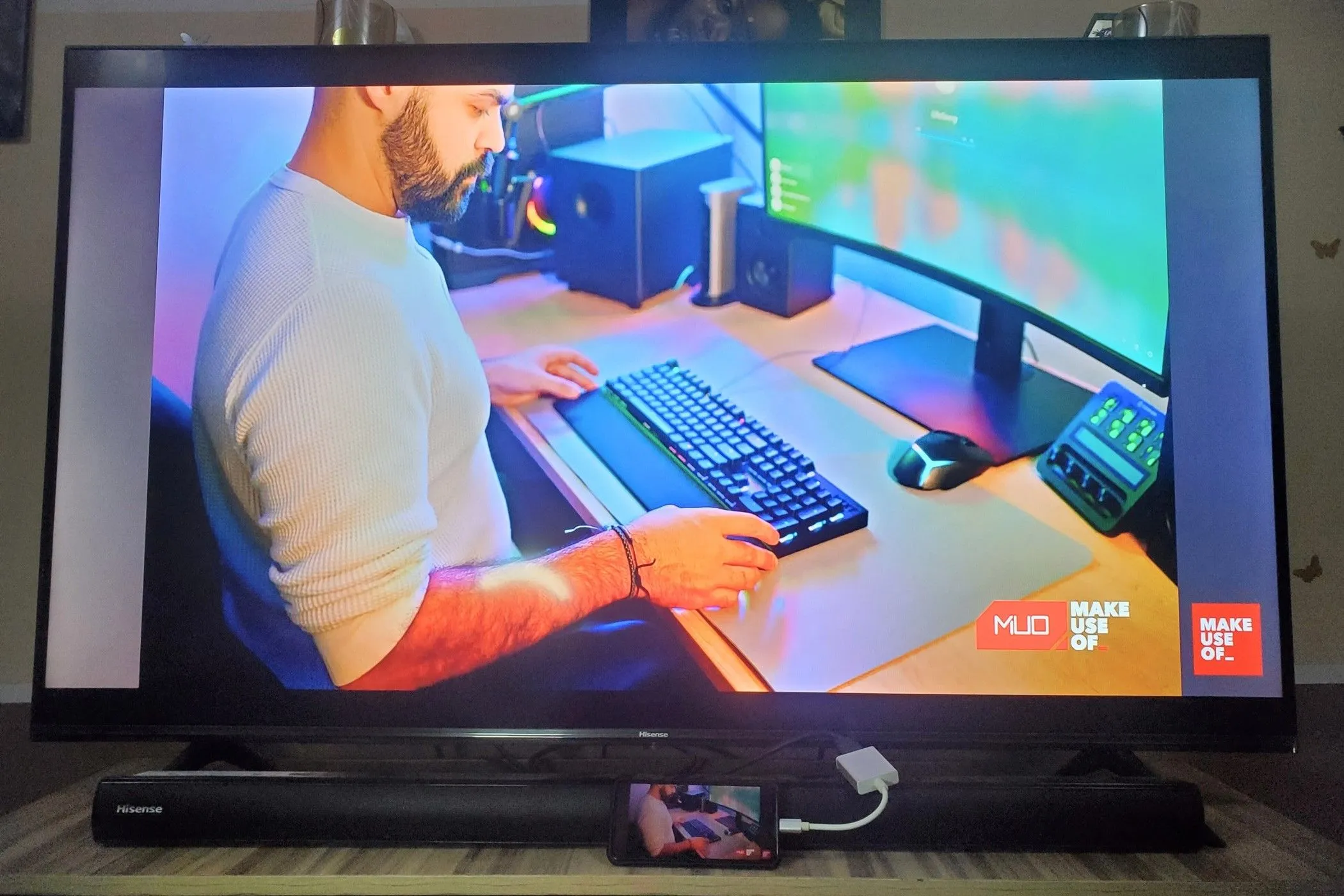 Điện thoại thông minh kết nối với TV qua adapter USB-C sang HDMI, hiển thị giao diện desktop và người dùng đang gõ bàn phím