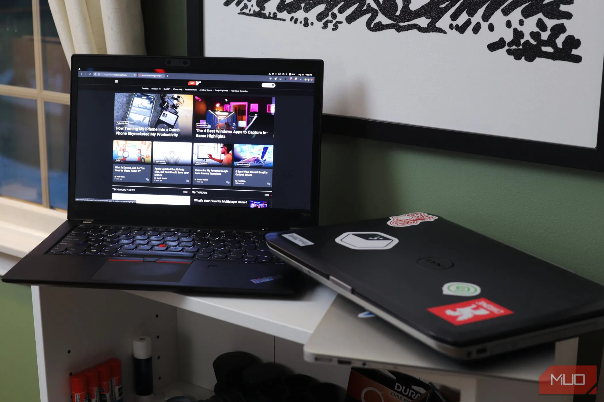 Hai chiếc laptop trên kệ trắng, tượng trưng cho việc chia sẻ thiết bị và rủi ro bảo mật.