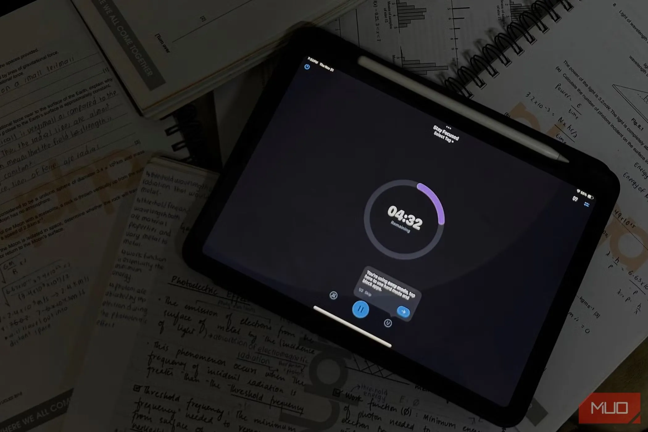 iPad hiển thị bộ đếm thời gian học tập cùng với sổ ghi chú và bút trên bàn