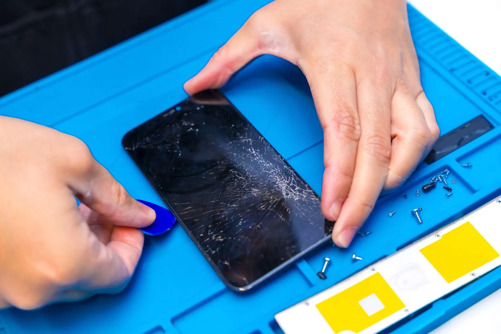 Kỹ thuật viên đang cẩn thận tháo mở smartphone để sửa chữa tại trung tâm bảo hành
