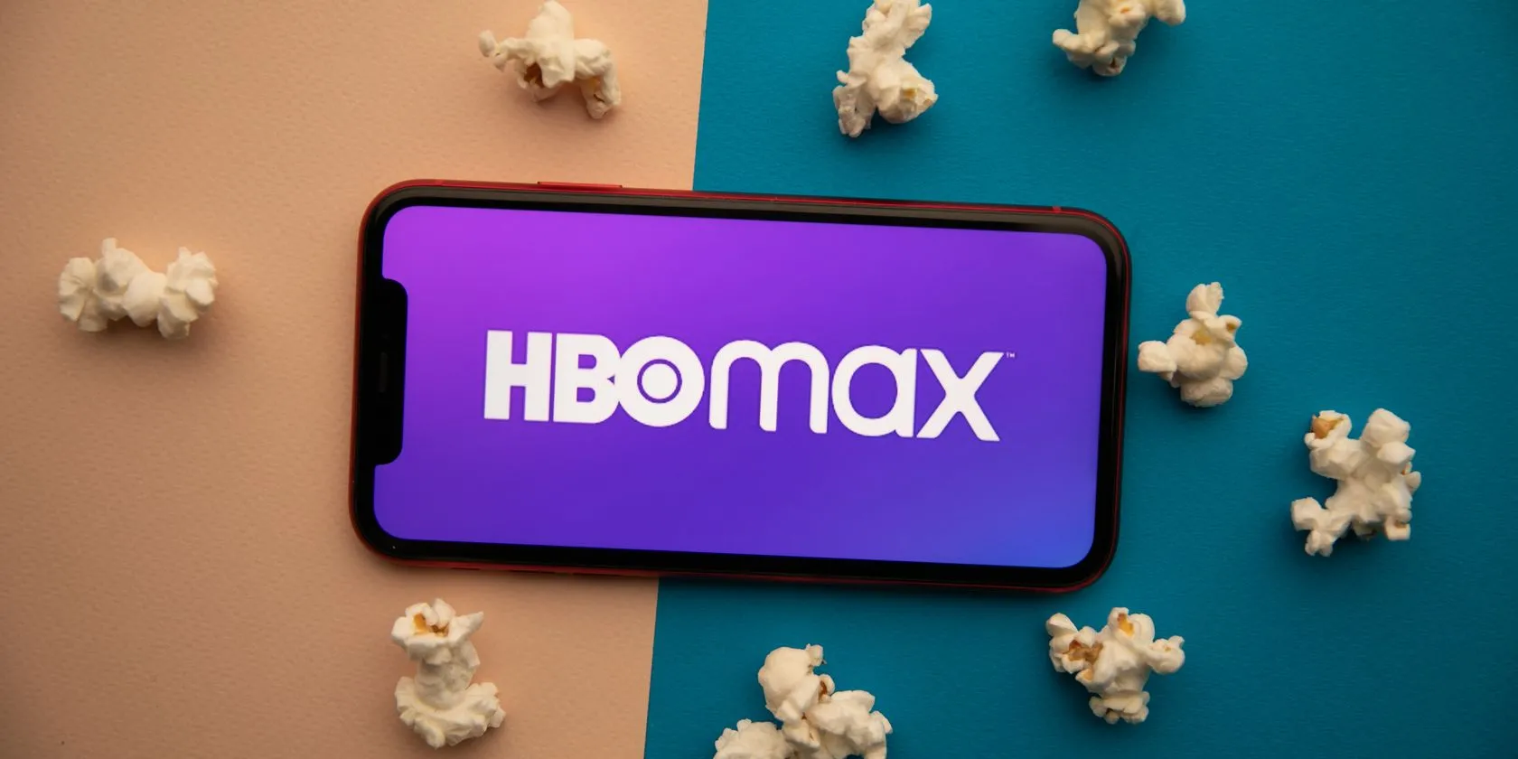 Logo HBO Max nổi bật trên màn hình điện thoại, bên cạnh đĩa bỏng ngô, gợi cảm giác thư giãn và thưởng thức phim.