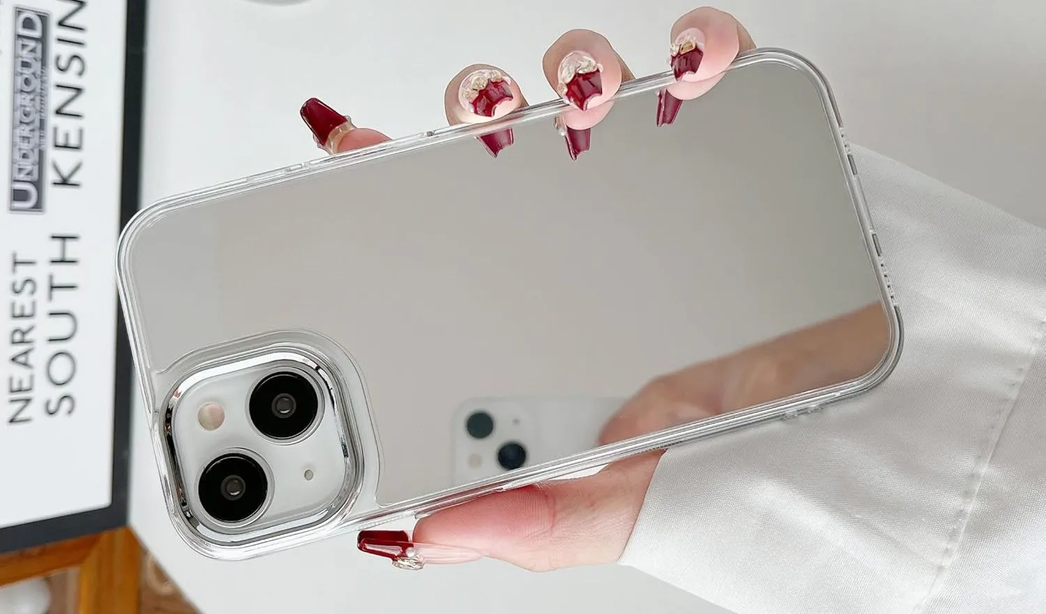 Một bàn tay đang cầm iPhone có ốp lưng với bề mặt phản chiếu giống gương, tận dụng mặt lưng làm gương khẩn cấp