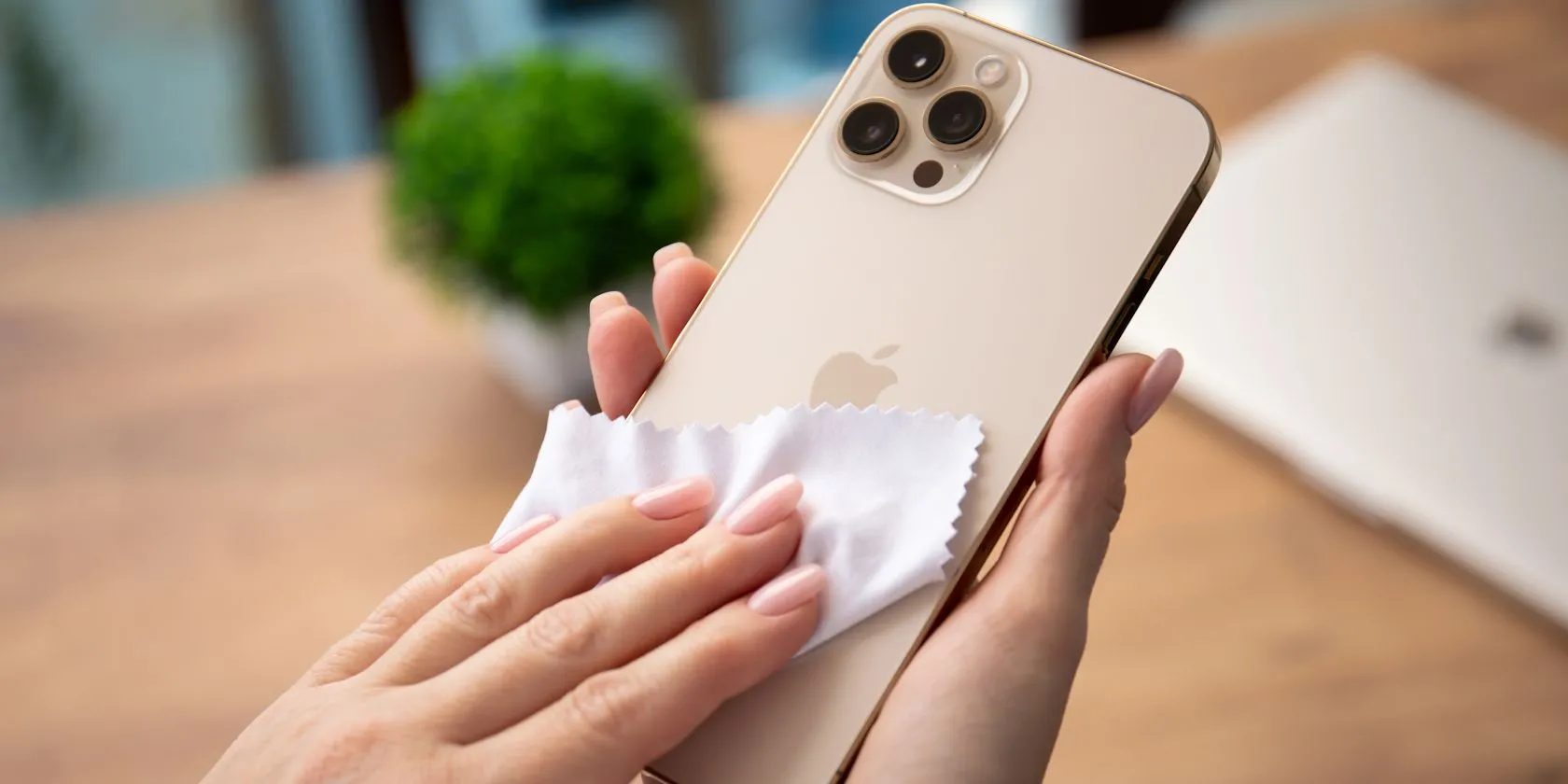 Người phụ nữ đang dùng khăn microfiber để làm sạch màn hình điện thoại iPhone