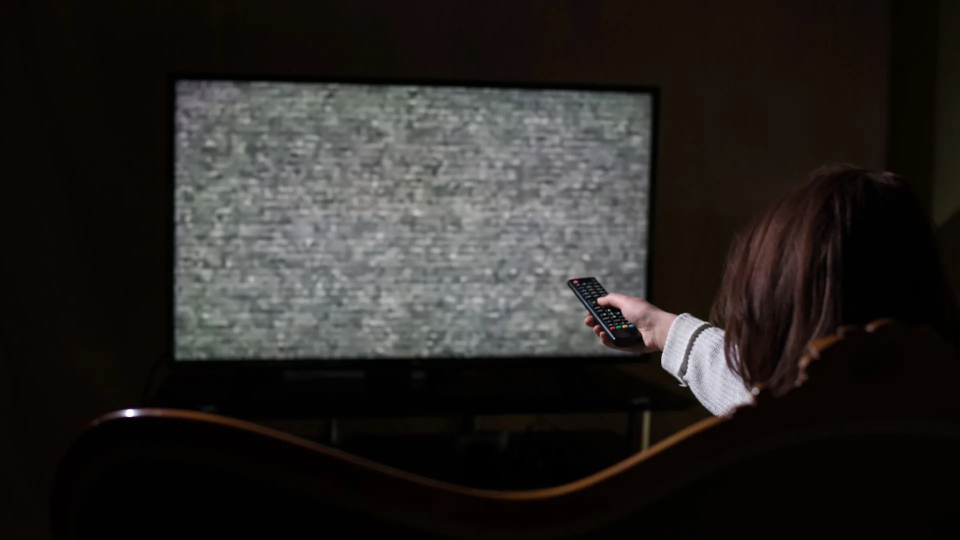 Người phụ nữ dùng điều khiển từ xa trước TV thông minh, minh họa dấu hiệu bị lỗi hoặc bị hack