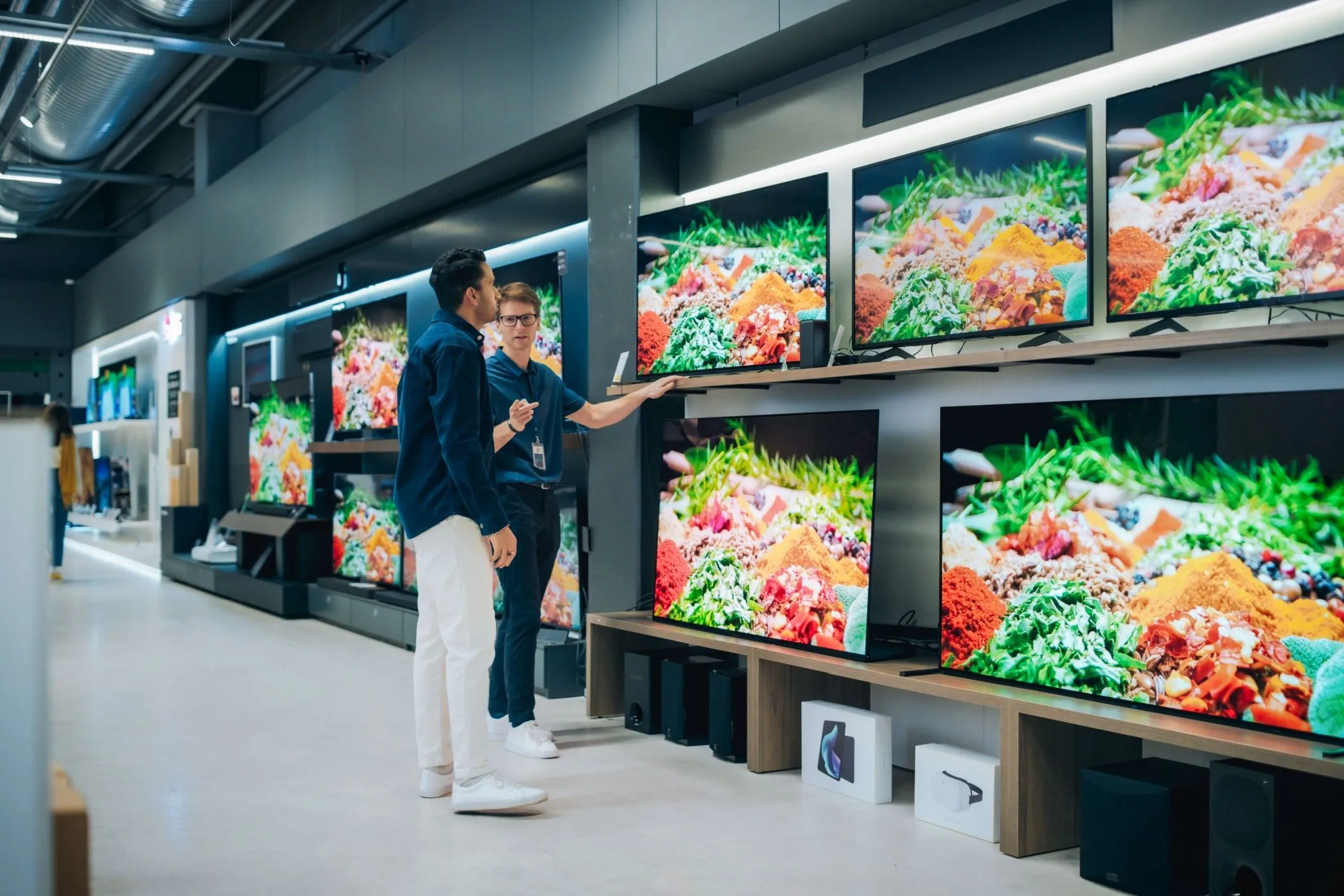 Nhân viên cửa hàng tư vấn TV cho khách hàng, minh họa trải nghiệm mua sắm cá nhân hóa và các ưu đãi hấp dẫn từ thẻ khách hàng thân thiết.
