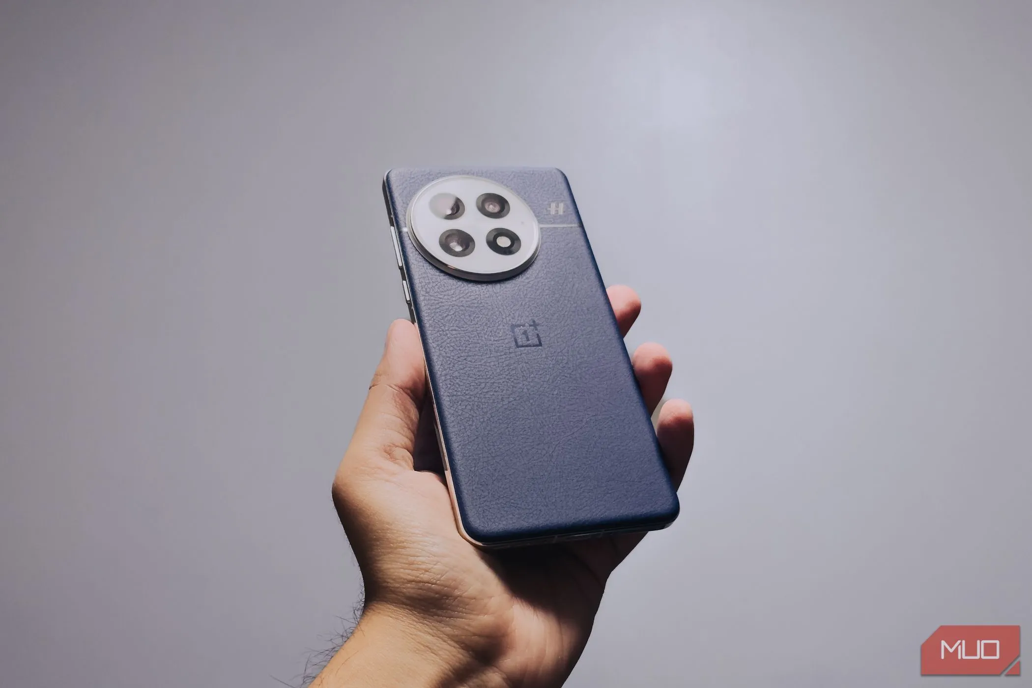OnePlus 13 màu đen được cầm trên tay, cho thấy công thái học cải thiện và khung nhôm phẳng.