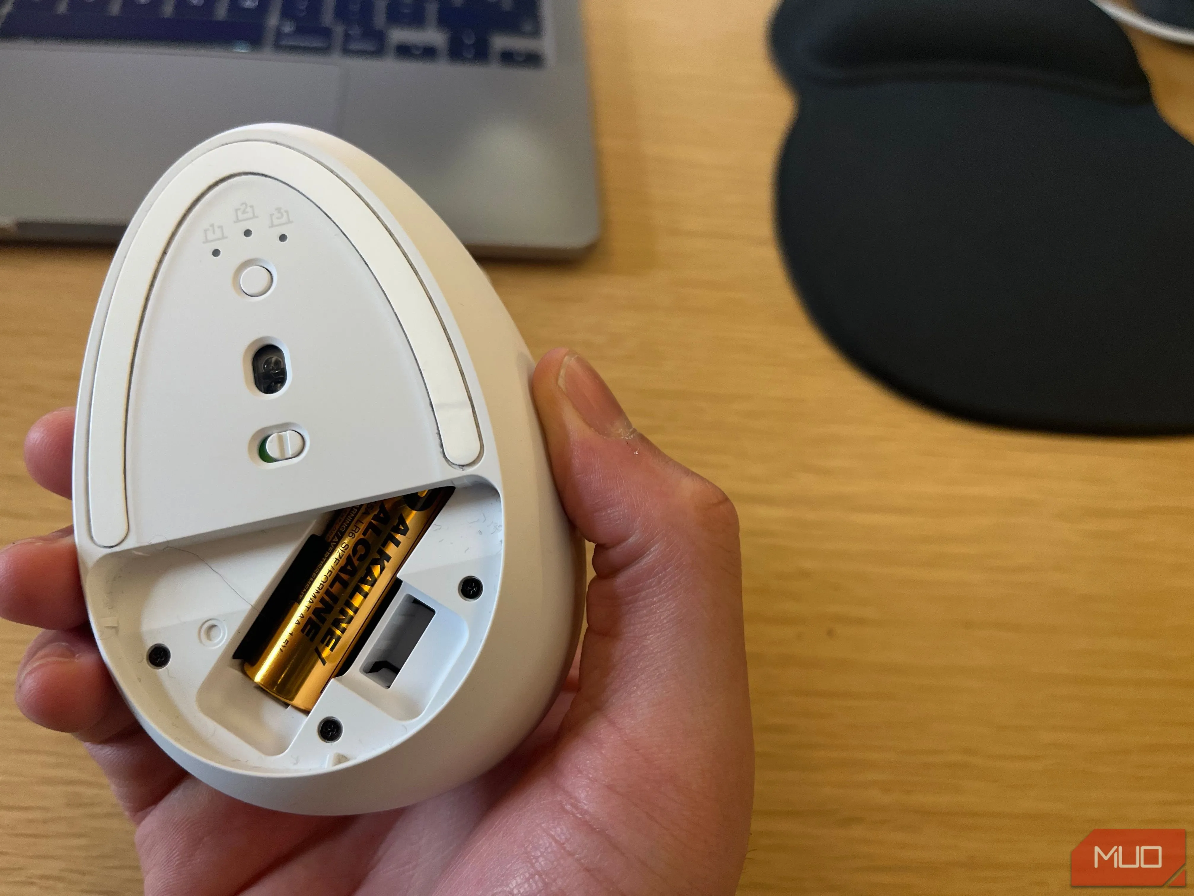 Pin AA rời bên trong khoang chứa của chuột không dây, minh họa vấn đề thay pin.