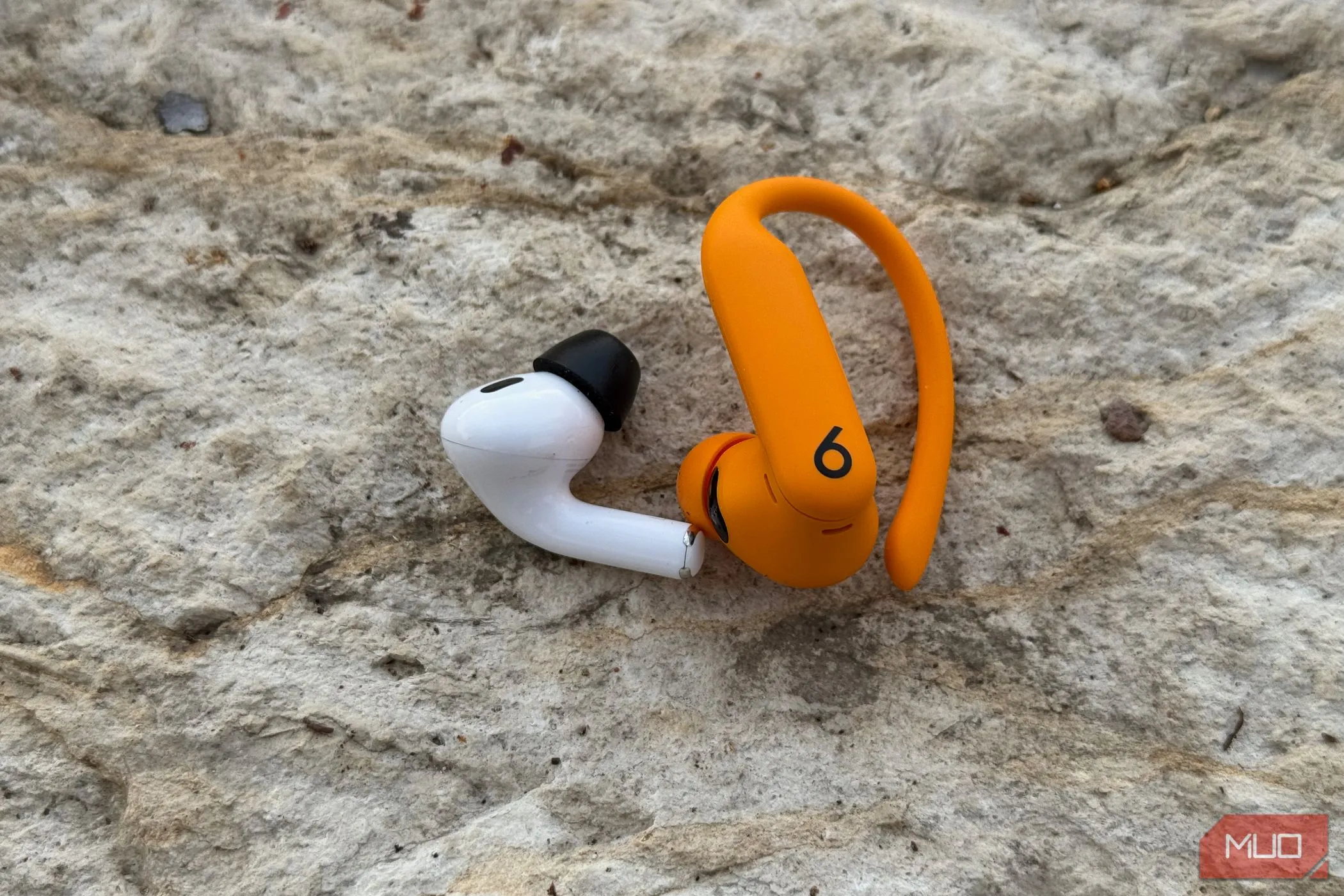 So sánh kích thước và thiết kế giữa tai nghe AirPods Pro 2 (trái) và Powerbeats Pro 2 (phải), thể hiện sự khác biệt về trọng lượng và độ thoải mái.