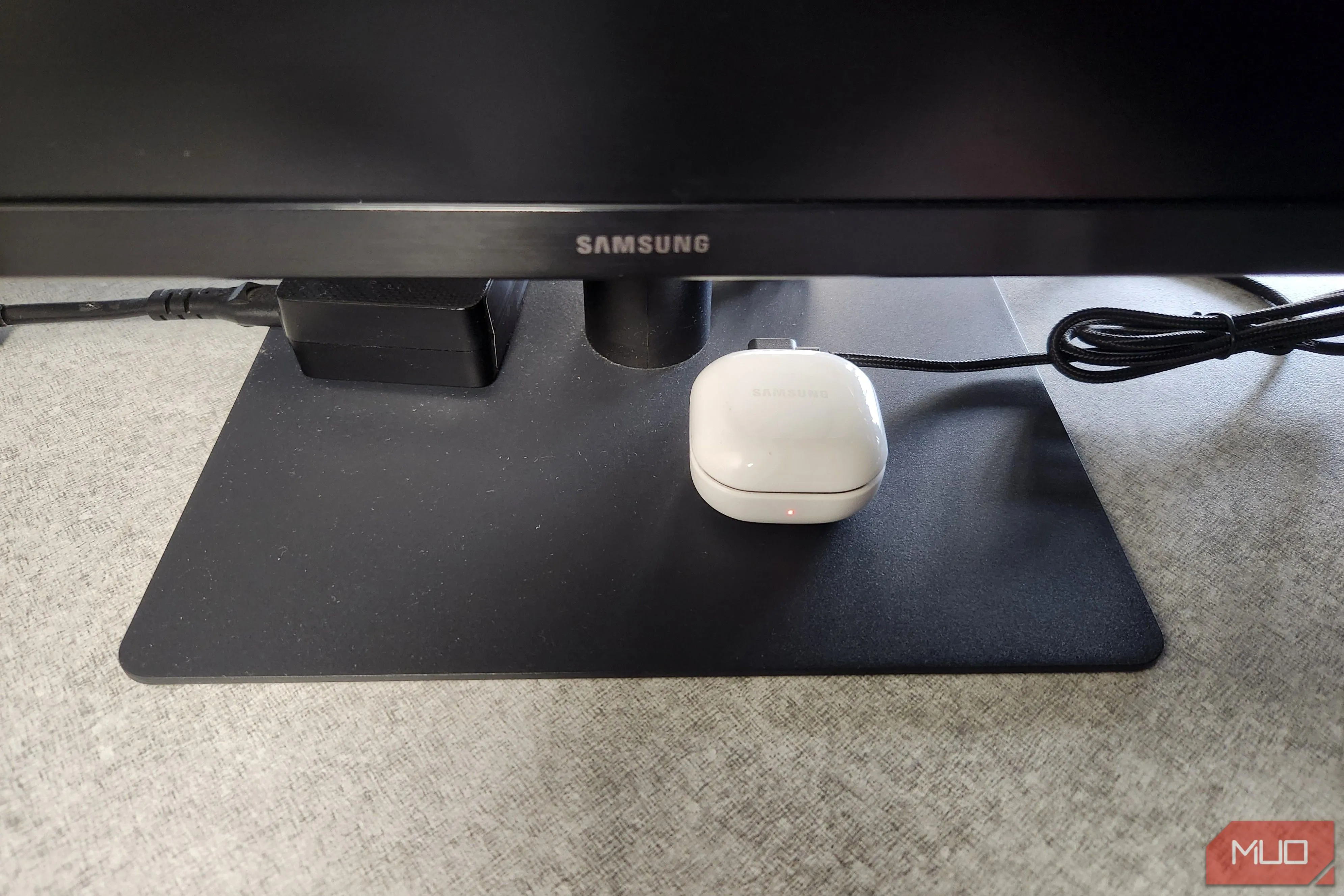 Tai nghe Bluetooth đang sạc qua cổng USB trên màn hình máy tính, minh họa việc cấp nguồn tiện lợi từ màn hình