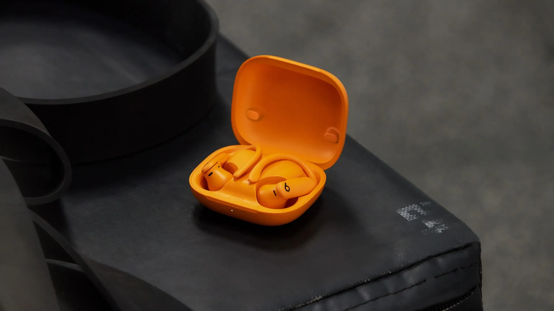 Tai nghe Powerbeats Pro 2 màu cam với thiết kế móc tai, làm nổi bật tính năng theo dõi nhịp tim hạn chế.