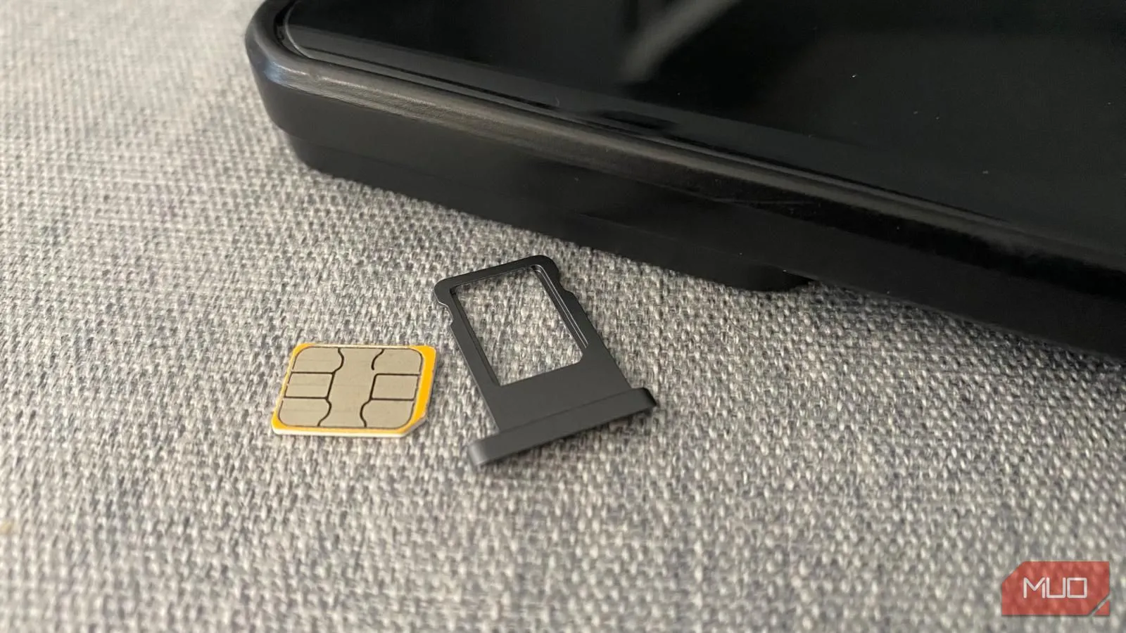 Thẻ SIM vật lý và khay đựng đặt cạnh điện thoại thông minh, biểu tượng của kết nối di động truyền thống